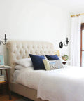 Black Wall Sconces Set Of Two Modern Farmhouse Candle Wall Lamps beside bed with tufted headboard in bright bedroom
