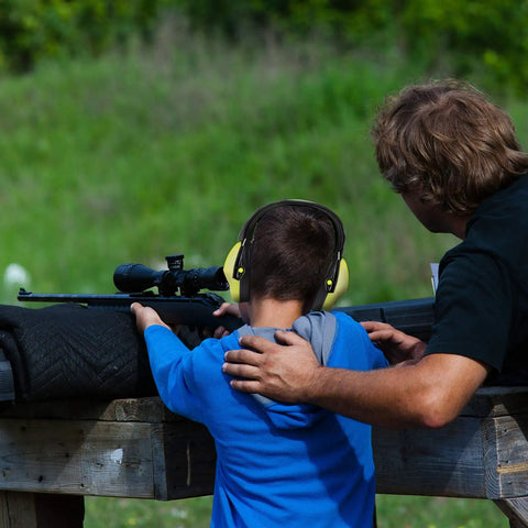 Child wearing Kids Noise Canceling Ear Muffs With 25dB NRR ANSI Certified Hearing Protection at shooting range with adult guide