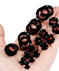 Hand holding Ultra Thin Silicone Ear Gauge Stretching Kit 4mm to 20mm Black Soft Flexible Tunnels Plugs for Earcare