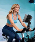 Woman using stationary bike with tablet mount in gym