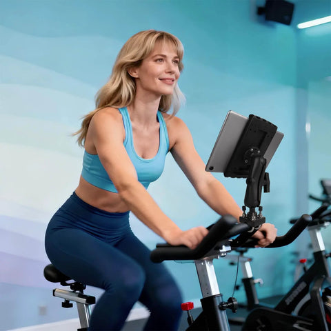 Woman using stationary bike with tablet mount in gym