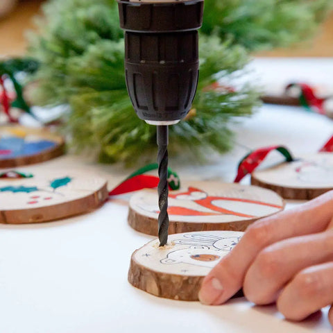 Close-up of Pink Cordless Drill Set for Women in use drilling into wooden crafts with festive designs, showing drill bit in action.