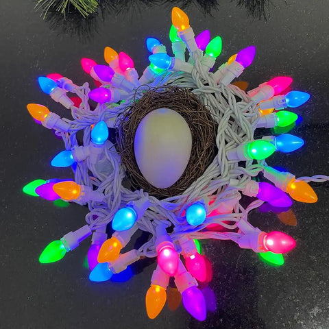 Pastel Easter String Lights 50 LED C3 Glass Bulbs, 12.5 Ft White Wire wrapped around a nest with an egg, multi-color glow