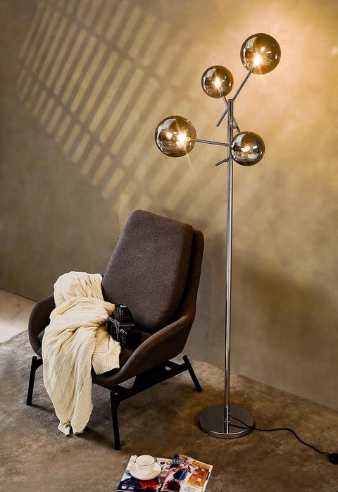 Sputnik 4 Light Floor Lamp With Smoky Grey Glass Globes, Chrome Finish, next to a chair in a living room setting