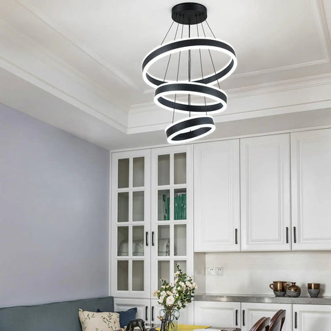 Modern Black LED Ring Chandelier With Three Adjustable Tiered Cylinders hangs over a kitchen island with bright white illumination.