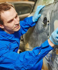 Person using 45 Piece Wet And Dry Sandpaper Set Workhorse Grit Range 120 To 5000 on car for auto polishing, wearing blue work suit