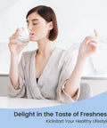 Woman with short brown hair in a beige robe drinking water from a glass mug in a bright kitchen; blue curved banner at bottom.