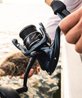 Rekon Spinning Fishing Reel Combo With 7 Foot Heavy Action Rod And 3000 Reel For Saltwater held on a boat, dark gray finish visible.
