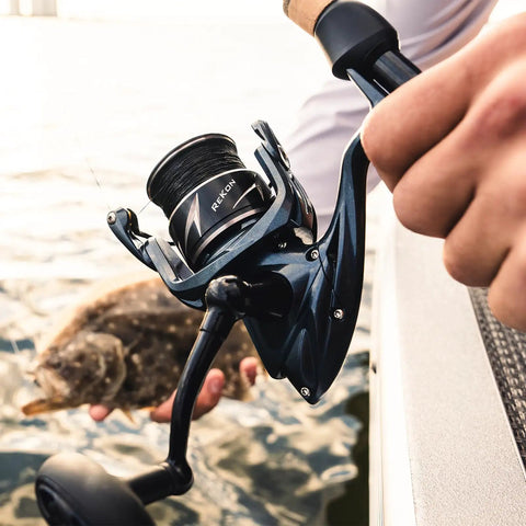 Rekon Spinning Fishing Reel Combo With 7 Foot Heavy Action Rod And 3000 Reel For Saltwater held on a boat, dark gray finish visible.