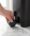 Person attaching an 8 Pack Tough Nylon Stem Swivel Casters 1.5 Inch to a utility bin for easy mobility.