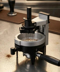 Heavy Hitter Rotary Espresso Puck Distributor Tool Featuring Adjustable Height And 12 Precision Points To Crush Clumps leveling coffee grounds on a stainless steel counter.