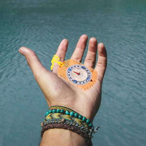 Hand holding Top Notch High Precision Survival Hiking Compass With Bright Orange Lanyard Portable Multi Function Orienteering Tool