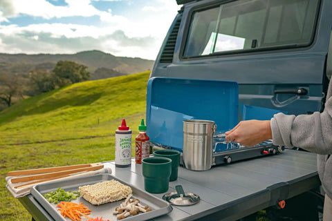 Preparing meal outdoors with Go 4 Piece Stainless Steel Camp Cook Set, 32 ounce pot, lid, cups; perfect for hikers and campers.