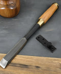 Wood chisel with wooden handle and black metal door latch set on a wooden and gray background