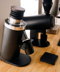 Heavy Duty 64Mm Flat Burr Electric Coffee Grinder Designed For Single Dosing Habits With Anti Popcorn Guard And Zero Static Hiccups in glossy black on wooden table.