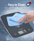 Cleaning a black digital kitchen scale with LCD display and tare function, showing easy maintenance for home cooks.