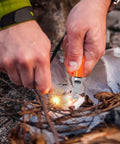 Person using Three Pack Ferro Rod Fire Starters With Scraper Striker to ignite fire in outdoor setting