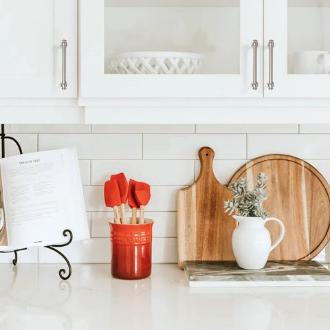 Kitchen counter with decorative board, utensils, and white cabinets featuring 10 Pack Matte Black 3 Inch Cabinet Handles For Kitchen Cabinets And Cupboards.