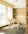 Wood-paneled room with dining table and chairs by large windows, showing modern rustic design.