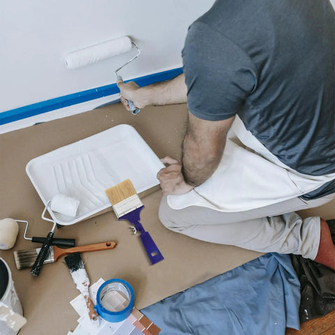 Person painting wall with tray and paint brushes, including Three Inch Adjustable Flat Tip Paint Brush With 270 Degree Rotatable Head.