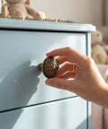 Hand reaching for Old School Brass Cabinet Knob Set, Solid Zinc Alloy 1.4 Inch Round Handles, Antique Style, on drawer