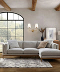 Living room with Two Light Wall Sconce With White Fabric Tapered Shades In Dope Antique Brass Finish above a gray sectional sofa.