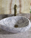 Sleek Marble Vessel Sink For Modern Bathrooms Featuring An Oval Countertop Basin Design with polished marble surface and golden faucet.