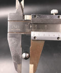 Caliper gauge measuring a metal strip; knurled thumb screw and metric and inch scales visible.