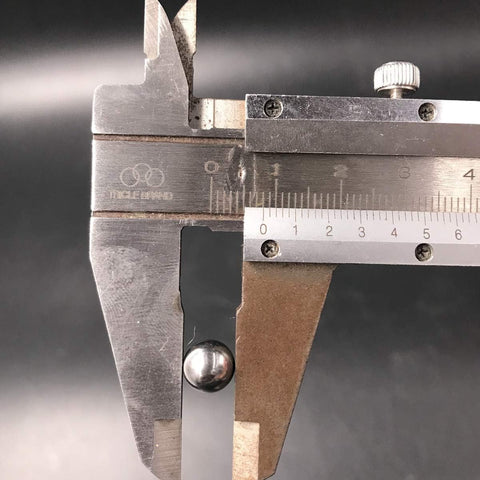 Caliper gauge measuring a metal strip; knurled thumb screw and metric and inch scales visible.
