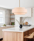 Totally Iconic 24 Inch Linen Drum Chandelier With Six Warm Lights Featuring Sleek Gold Frame And Three Tier Vintage Farmhouse Design hanging in a kitchen.