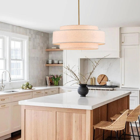 Totally Iconic 24 Inch Linen Drum Chandelier With Six Warm Lights Featuring Sleek Gold Frame And Three Tier Vintage Farmhouse Design hanging in a kitchen.