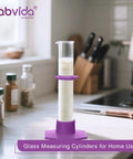 Durable Pro Grade Borosilicate Glass Measuring Cylinder Set With Hex Base And Brush Includes 10 ML 25 ML 50 ML And 100 ML Cylinders Class B Lab Glassware For Chemistry Experiments And Education, shown in a kitchen setting on a counter.