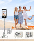 Phone Camera Grip With Selfie Stick Tripod Magnetic Mount And Detachable Wireless Shutter Button for iPhone, standing on beach.
