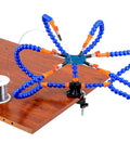 Six Flexible Arm Helping Hands Soldering Station With Silicon Clip Tips clamped to a wooden table, shown with solder wire spool.