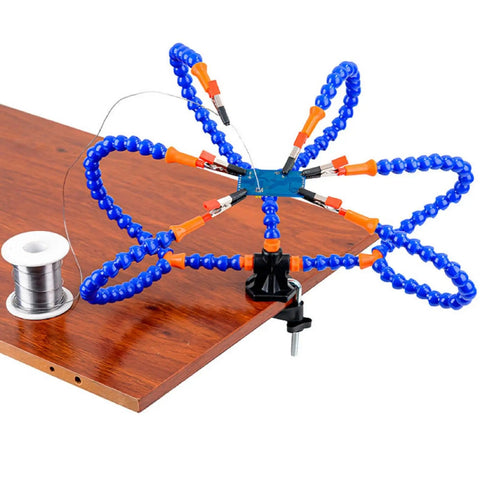 Six Flexible Arm Helping Hands Soldering Station With Silicon Clip Tips clamped to a wooden table, shown with solder wire spool.