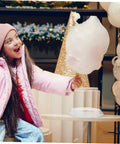 Child holding cotton candy next to Cotton Candy Machine Guard Cover For Sugar Floss Makers Lightweight And Reusable Enclosure Easy To Clean Indoor Use Mess Free Protection That Keeps Little Fingers Safe And Your Countertop Clean.