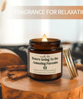 Celebrate The Freshly Minted Arrival Of New Mama And Papa With This Awesome Gift Set For Couples Featuring Matching Tumblers Paired With A Warm Cozy Candle Perfect For Baby Showers First Fathers Day And Parenting Squad Celebrations. Brown candle labeled 'You're Going To Be Amazing Parents' on a wooden table.
