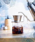 Close-up of Tsubame WDS185 Stainless Steel Coffee Dripper For 2 To 4 Folks With Wave Filter 185 in use, pouring into a glass carafe.