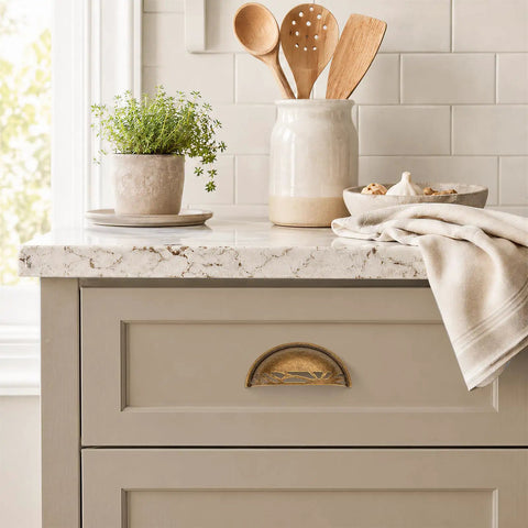 Three Pack Antique Brass Half Moon Cup Pulls For Kitchen Cabinets And Drawers Featuring Hella Smooth Finishes And Rock Solid Zinc Alloy Build With Detailed Cuts That Bring Fresh Charm To Furniture And Vanity Projects Quick And Easy mounted on a light gray cabinet.