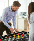 Two adults playing foosball on a 49 Inch 4 In 1 Combo Game Table Featuring Fast Swap Foosball Slide Hockey Ping Pong And Pool Tops Built For Adult Game Rooms Weekend Warrior Sessions And Chill Hangouts.
