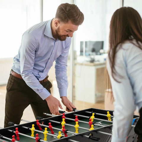 Two adults playing foosball on a 49 Inch 4 In 1 Combo Game Table Featuring Fast Swap Foosball Slide Hockey Ping Pong And Pool Tops Built For Adult Game Rooms Weekend Warrior Sessions And Chill Hangouts.