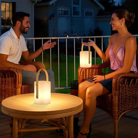 Two people on patio with Cordless LED Lantern Table Lamp With Remote, IP44 Shower Safe And Waterproof, providing warm light.