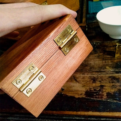 Wooden box with Brass Mini Folding Butt Hinges Set Four Pack, One Inch, installed on side, showing rust-resistant brass finish for smooth operation.