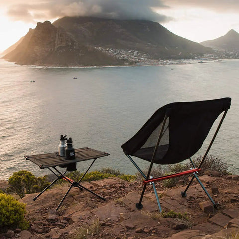 Ultralight Camping Table With Cup Holder And Carry Bag, Foldable Aluminum Backpacking Table set up on scenic hillside overlooking water