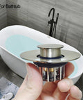 Tough As Nails Pop Up Tub Stopper With Integrated Hair Catcher And Fine Mesh Strainer in hand, showing stainless steel design.