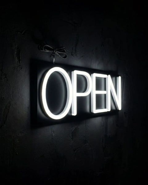 Lit White Neon Open Sign With Remote For Business Front Window Display 20x7 Inch LED Light Up Sign shown from an angle.
