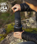 Person using Ultra Portable Travel Coffee Maker Kit For Grab And Go Outdoors All In One French Press Pour Over And Espresso Style Manual Brewer For Camping And Hiking Two Minute Brew For A Less Bitter More Flavorful Cup on a rock.