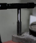 Metric And SAE Tap And Die 60-Piece Rethread Set in use, showing tap cutting internal threads in a metal piece.