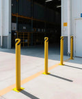 Rock Solid 2 Pack Carbon Steel Security Bollards, Heavy Duty 42 Inch Parking Barrier Posts with yellow powder coating in a warehouse.