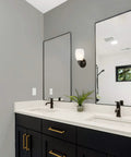 Bathroom interior with oil rubbed bronze wall sconce with frosted glass shade above vanity mirror, mounted up.